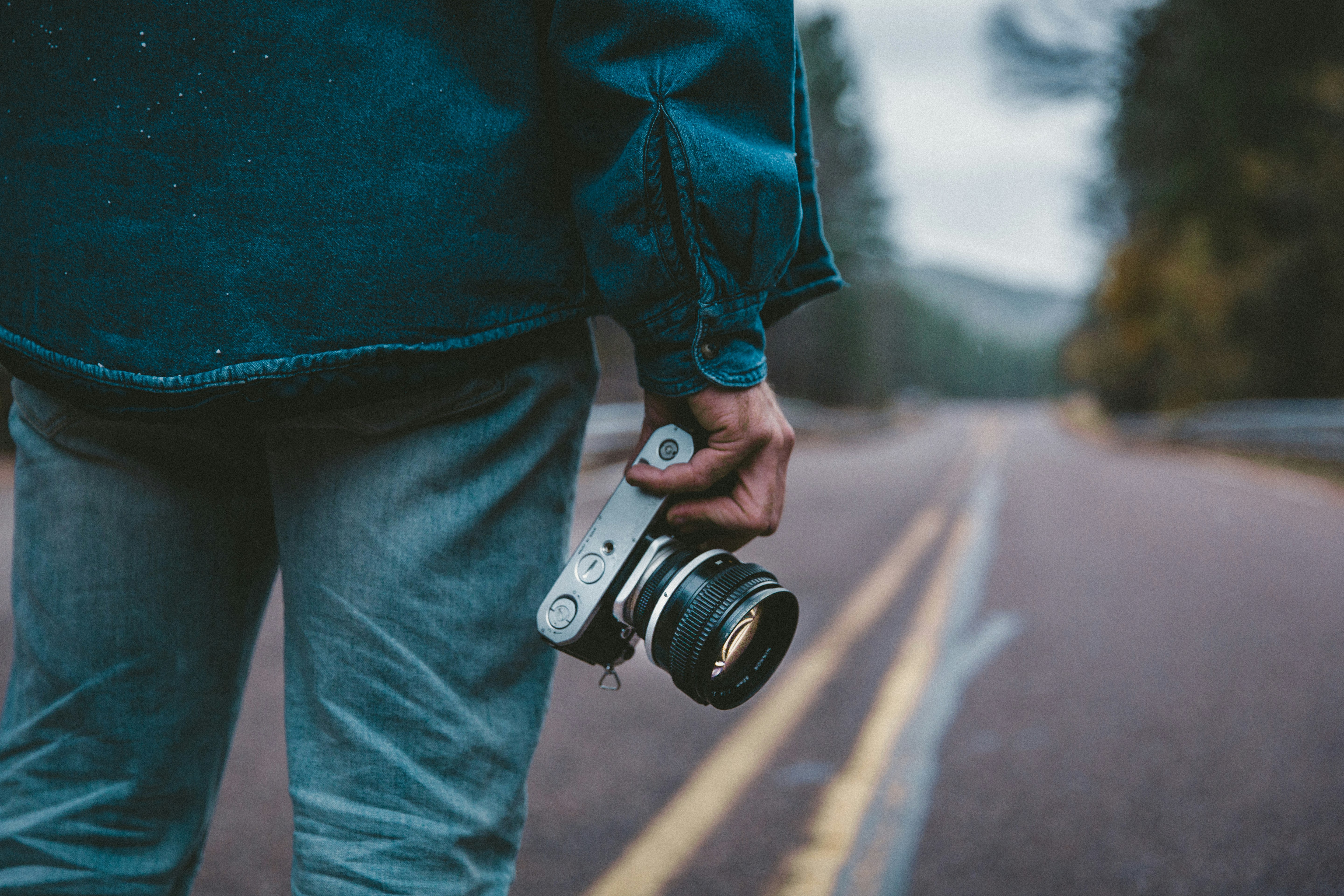 person holding gray and black camera while standing on road